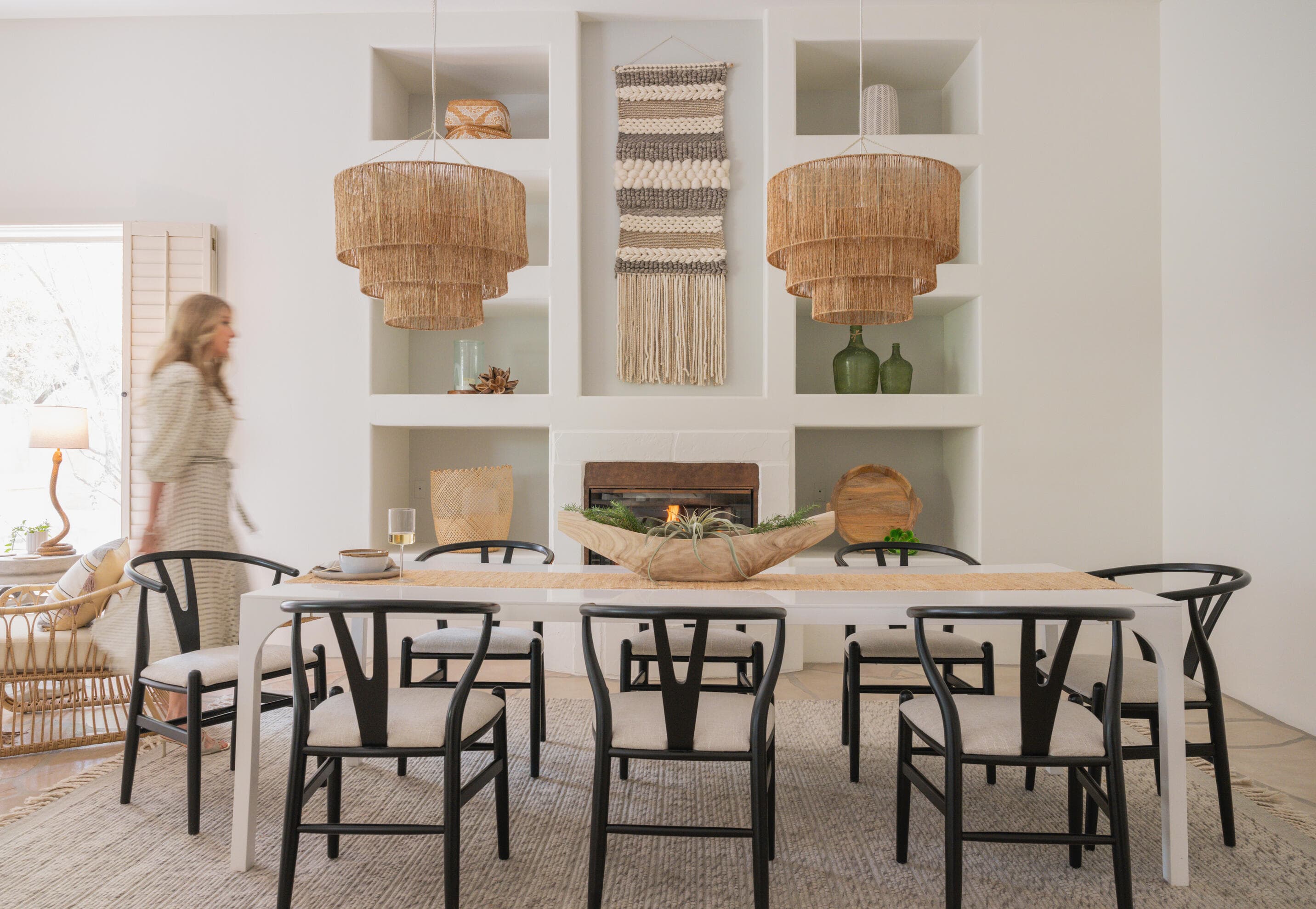 Wendy Lowell walking through a dining room she designed, with tiered jute pendants and white plaster niches